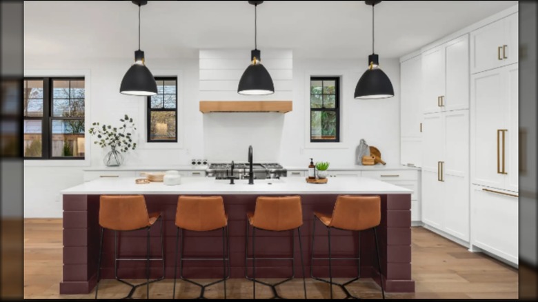 elegant burgundy kitchen island with black pendant lights and warm brown leather barstools.