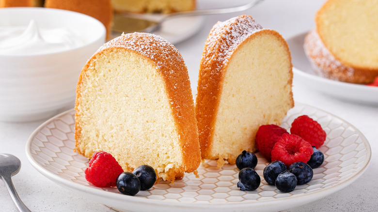 Pound cake with cream and berries on a white plate.
