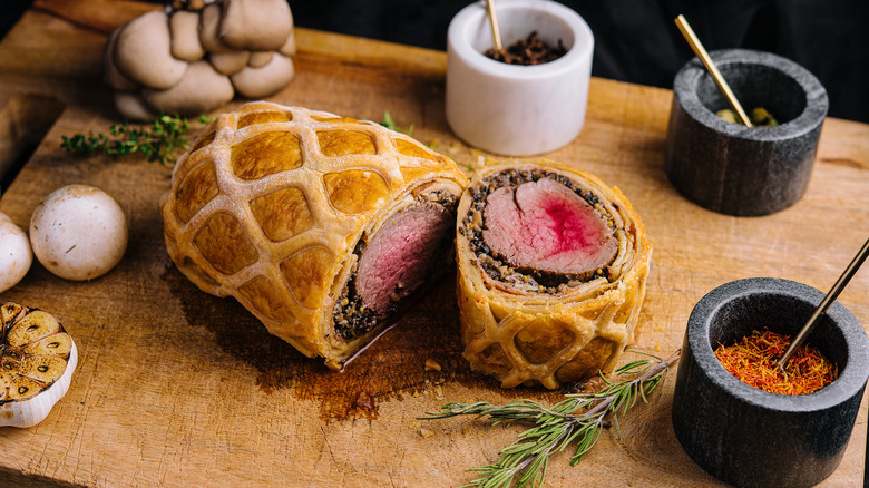 Beef Wellington on cutting board with spices and mushrooms