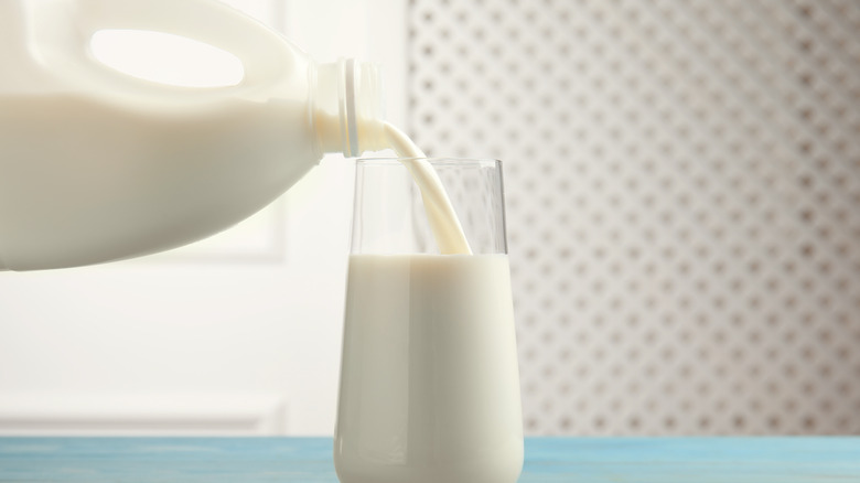 pouring pitcher of milk into glass