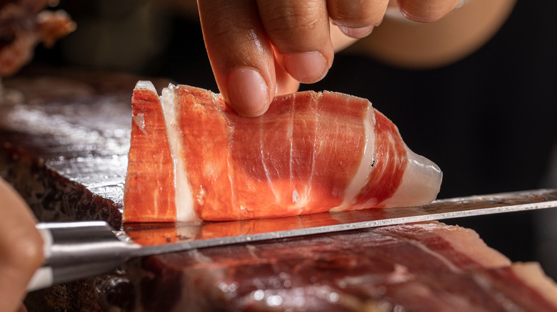 A chef cuts a slice of Iberico ham
