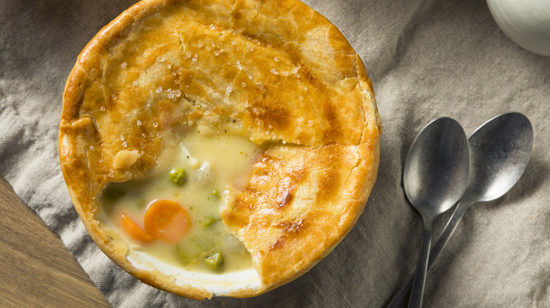 A overhead shot of a chicken pot pie with the crust broken to show the filling.