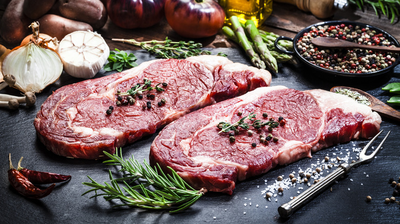 Two raw beef filets on a cutting board surrounded by ingredients