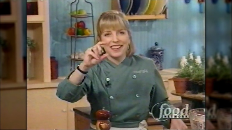Sara Moulton smiling in a green chef's jacket on the set of "Cooking Live"