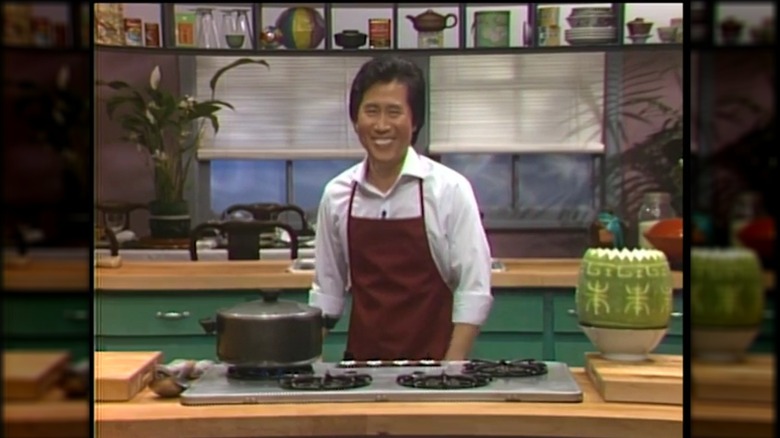 Chef Martin Yan in the 1980s, smiling in a red apron and white shirt, on the set of "Yan Can Cook"