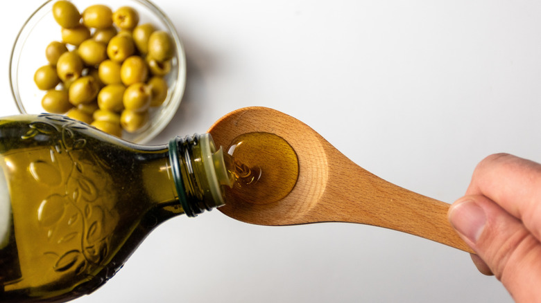 Pouring olive oil from bottle to spoon