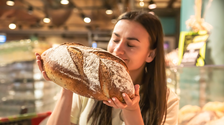 A satisfied customer smelling a high quality loaf of bread