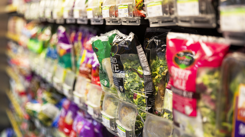 Assorted bagged salad kits on a grocery store shelf