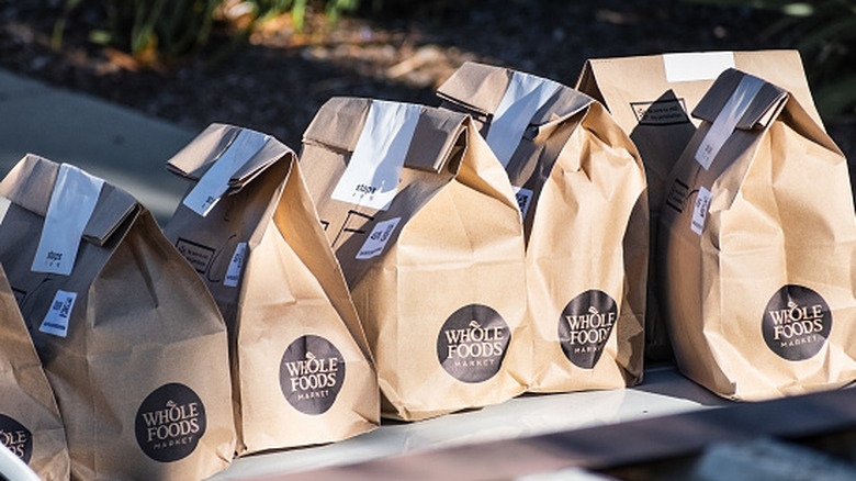 A line of Whole Foods brown paper bags willed with delivery groceries