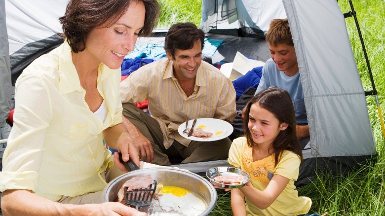 Camping family eating bacon and eggs