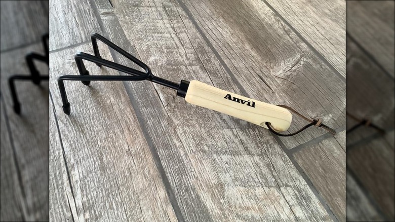 Anvil wood handle hand cultivator on a wood floor
