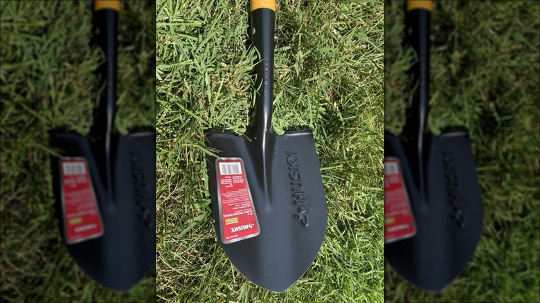 Close-up of the end of the Husky shovel laying in the grass with a red label.
