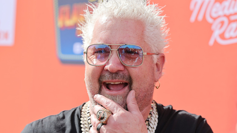 Guy Fieri smiling with hand on chin