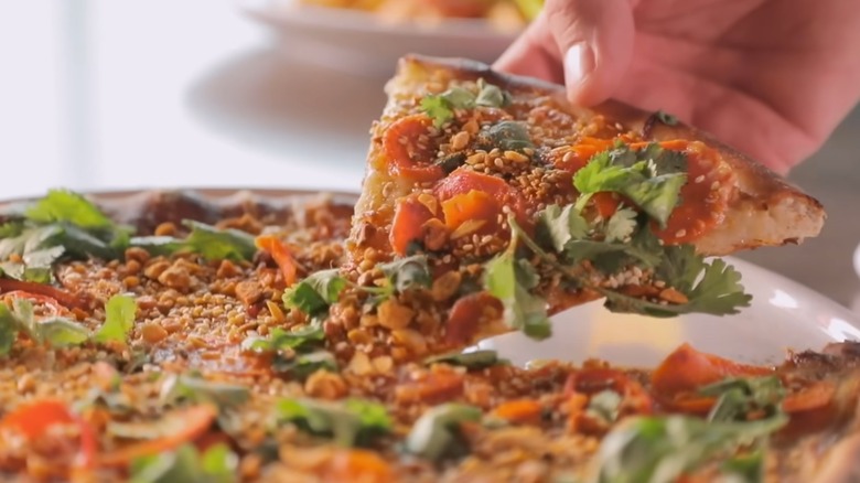 hand taking a slice of Roasted Carrot Pizza from Weights and Measures