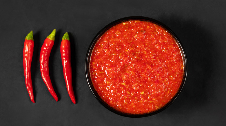 Harissa in bowl next to red chilis