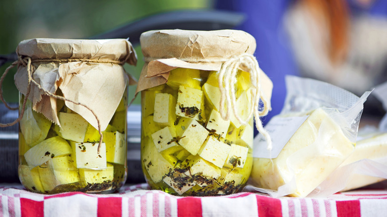 pickled feta cheese jars and block on red and white tablecloth