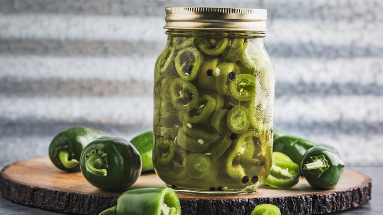 pickled jalapeno peppers jar and freshly sliced jalapenos on cutting board