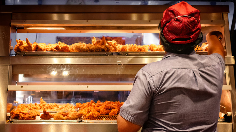 Food worker reaching for hot chicken