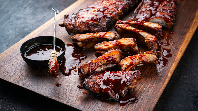 Two racks of baby back ribs on a cutting board with thick BBQ sauce