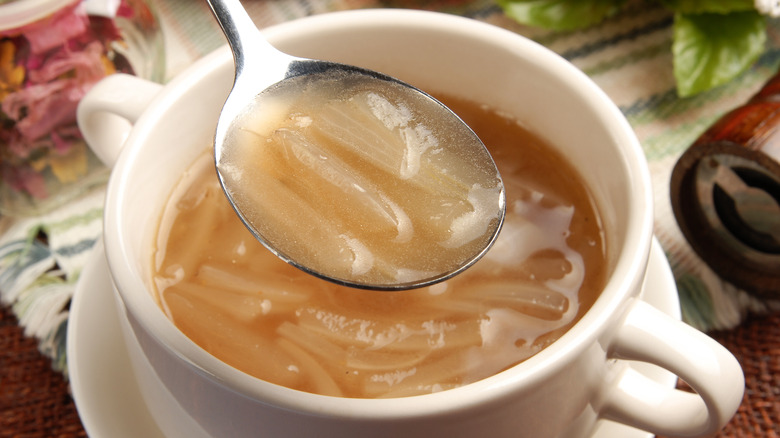 Spoon of French onion soup over bowl