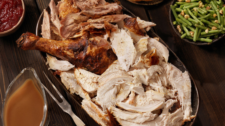 Thanksgiving turkey carved up into slices on a table with side dishes