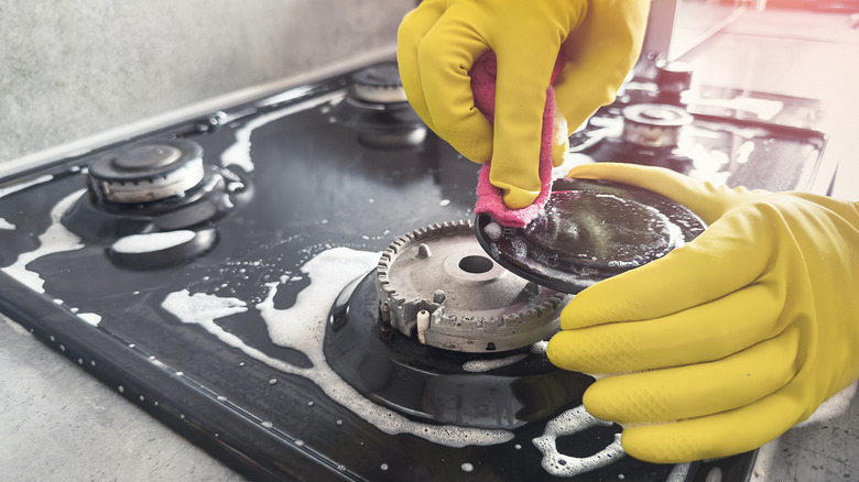 Someone cleans a stove top burner