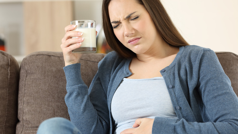 A woman looks sick while holding a glass of milk