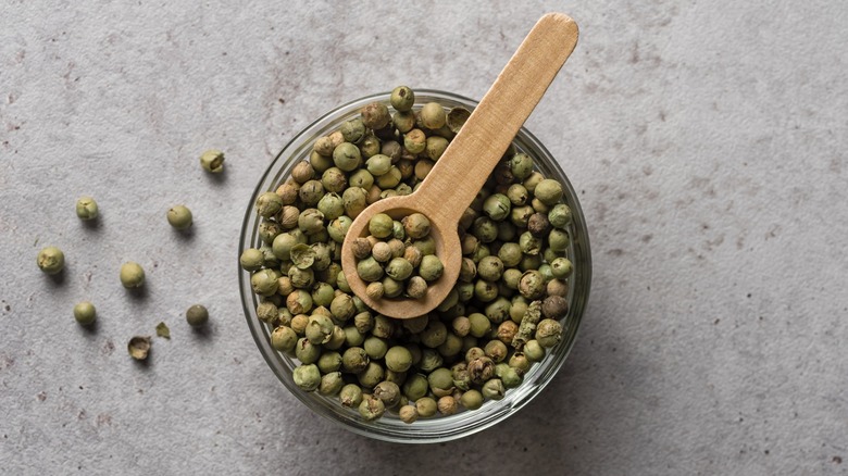 Dried green peppercorns in bowl with spoon