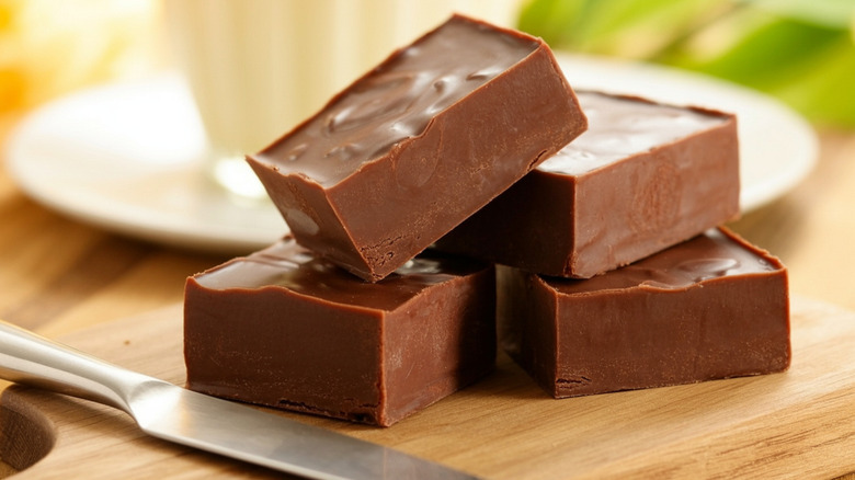 four pieces of fudge on a cutting board with a knife beside them