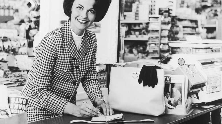 Woman writing a check in early 1970s at the grocery store