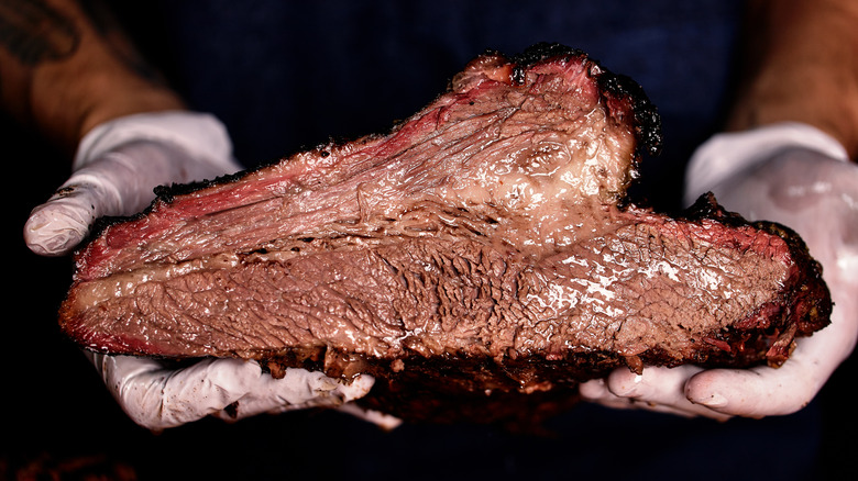 Close-up of hands holding smoked brisket