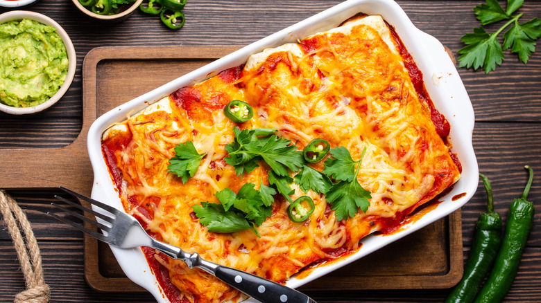 A pan of baked enchiladas with jalepeños and cilantro
