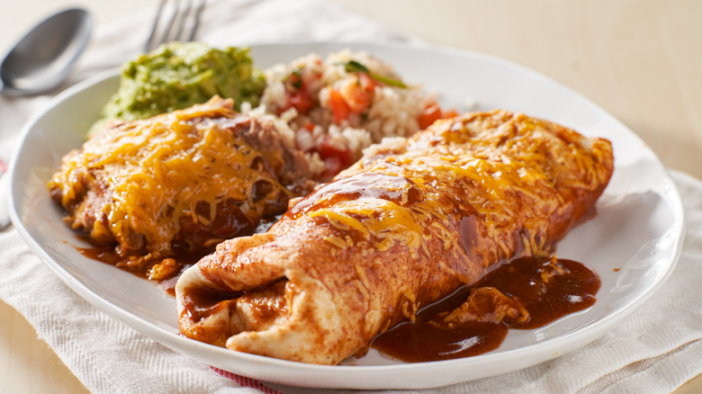 A wet burrito with rice, guacamole, and refried beans