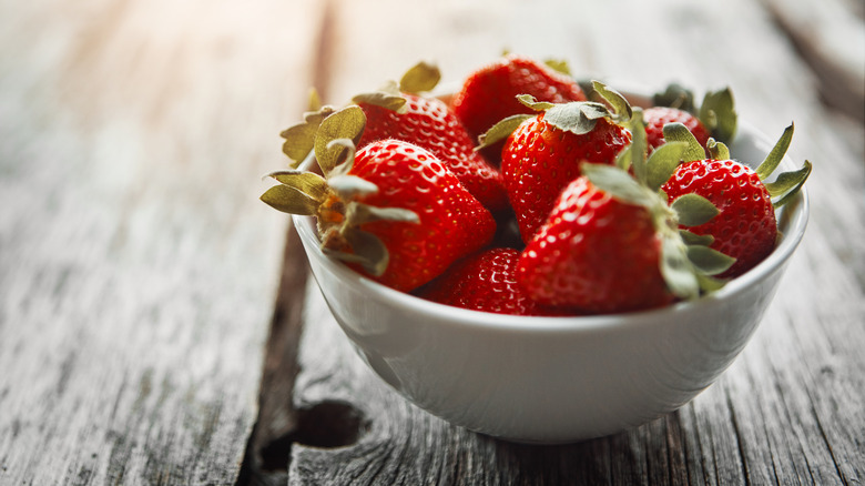 A small white bowl full of fresh strawberries