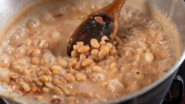 white beans cooking in a pot with a wooden spoon