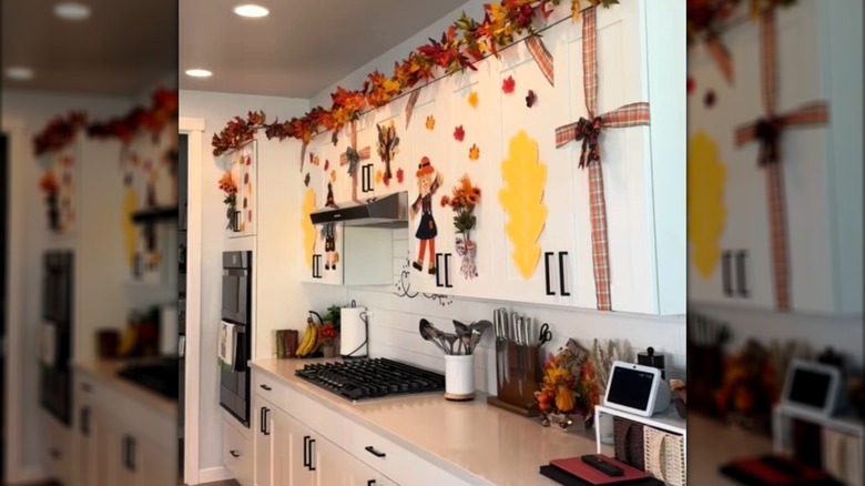 A white kitchen decorated with fall leaves and a maple leaf garland