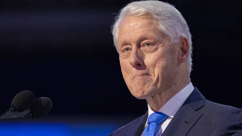 president bill clinton in a sideways profile, wearing a suit and a blue tie