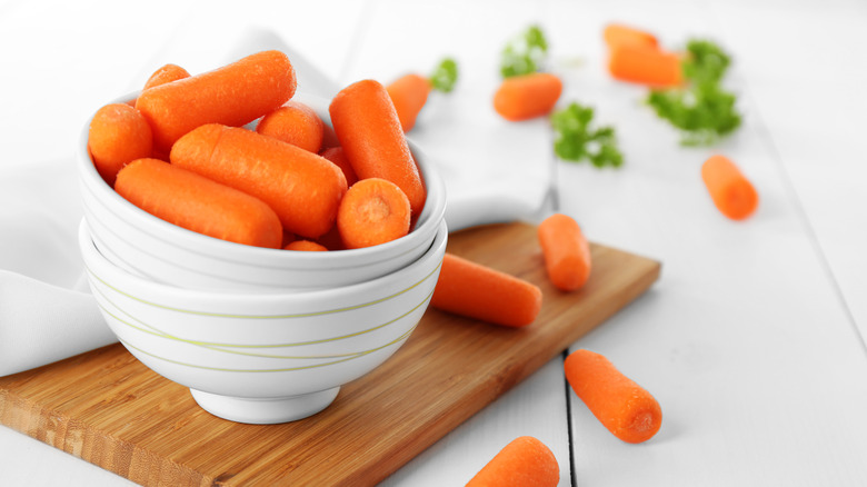 Baby carrots in a bowl on a board