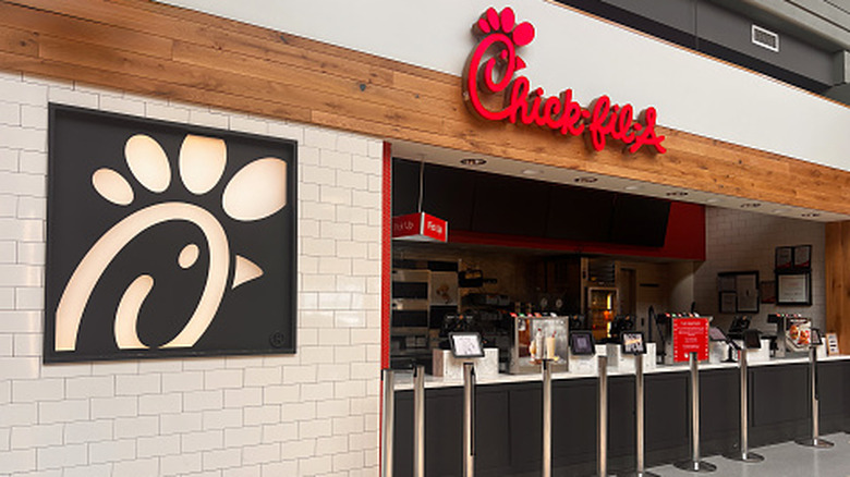 A Chick-fil-a station that is closed next to a giant version of the logo