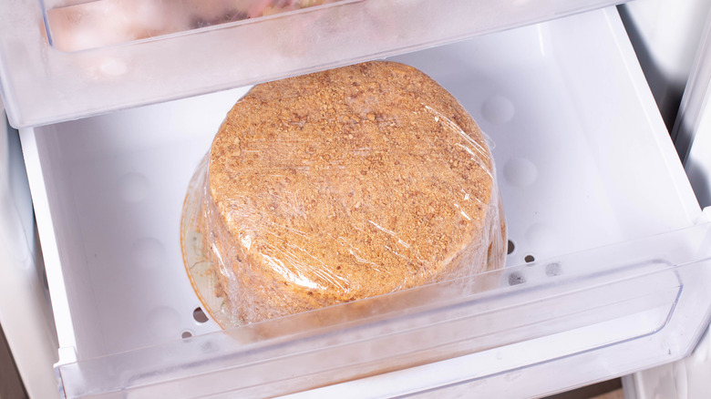 Cake wrapped in plastic wrap in freezer drawer