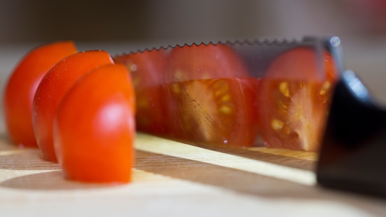Serrated knife slicing tomatoes