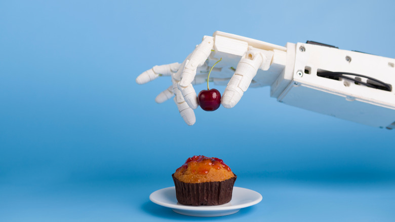 Robot hand garnishing a cupcake