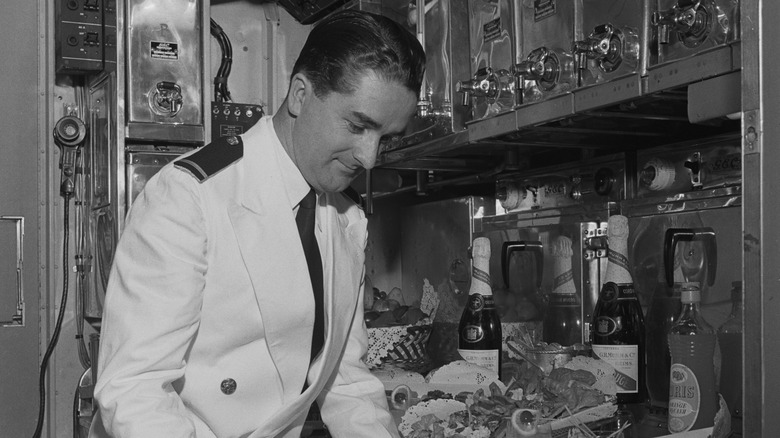 A flight attendant clearing dishes in a plane galley