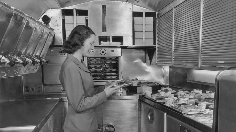 A stewardess in the plane's galley in the '50s preparing meals