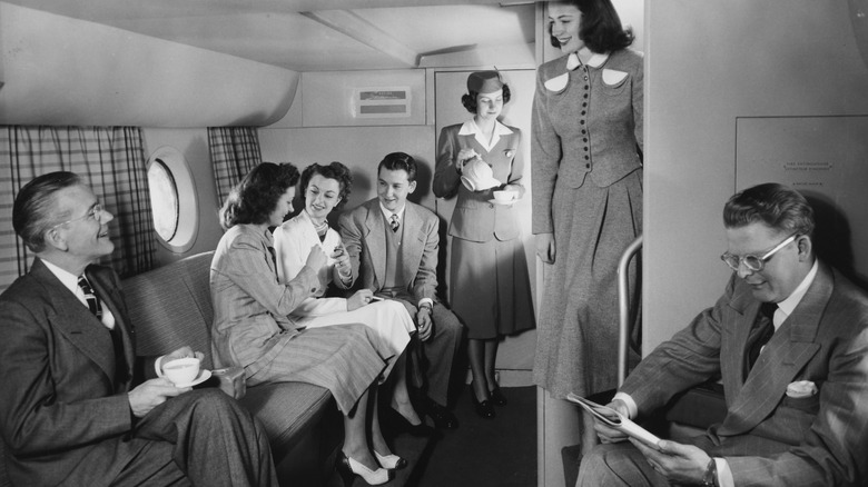 Guests relaxing in a social area of an airplane in the 1950s