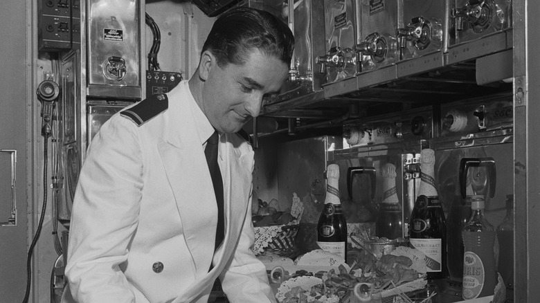 A flight attendant clearing dishes in a plane galley