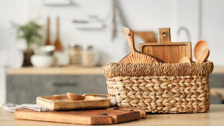 cutting boards and wooden spoons in a basket in a kitchen