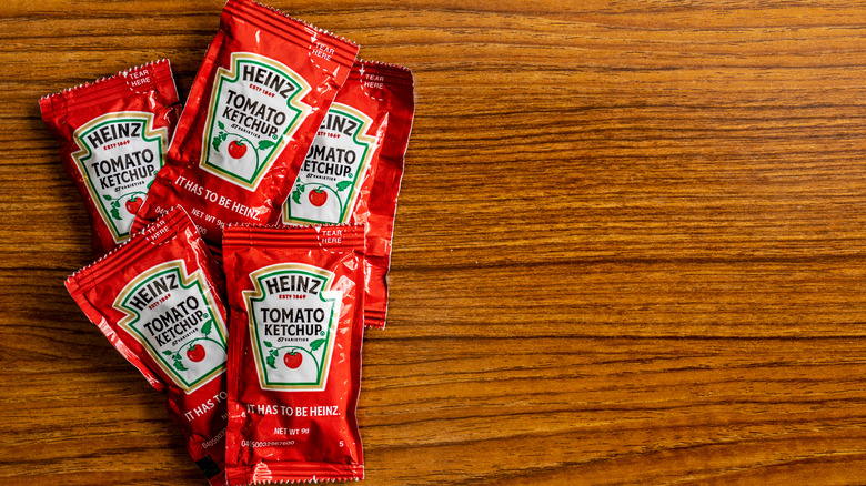 Five Heinz ketchup packets on wood background