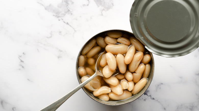 Open can of white beans with spoon