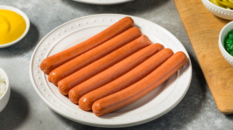 Uncooked hot dogs on plate